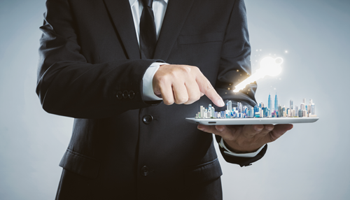 Man in suit pointing to a model city in his hand